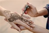 An image of henna being applied to a hand.