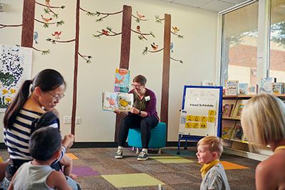 Librarian is reading a book to kids.