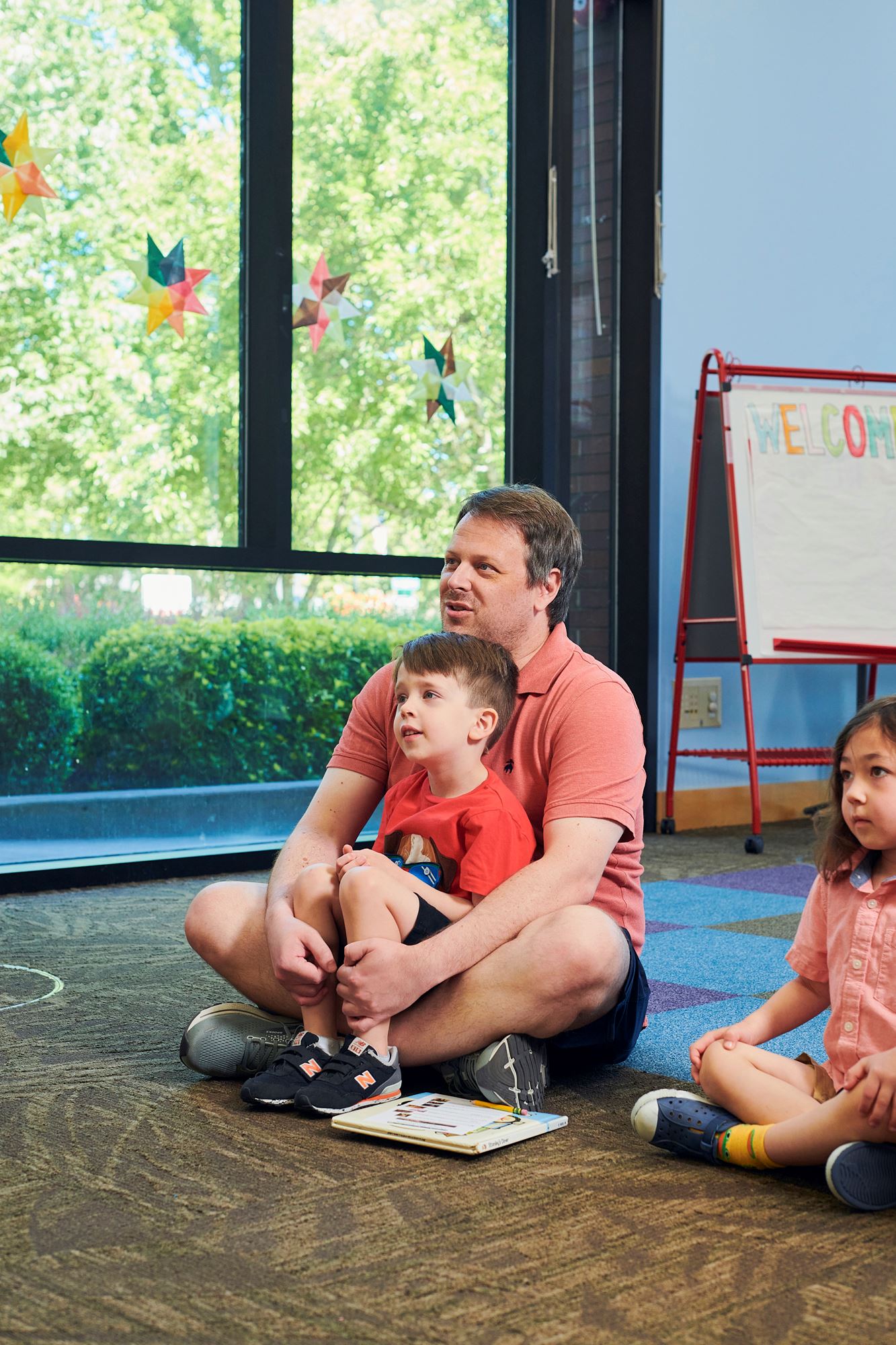 Photo of a man with a child sitting on his lap at library storytime.