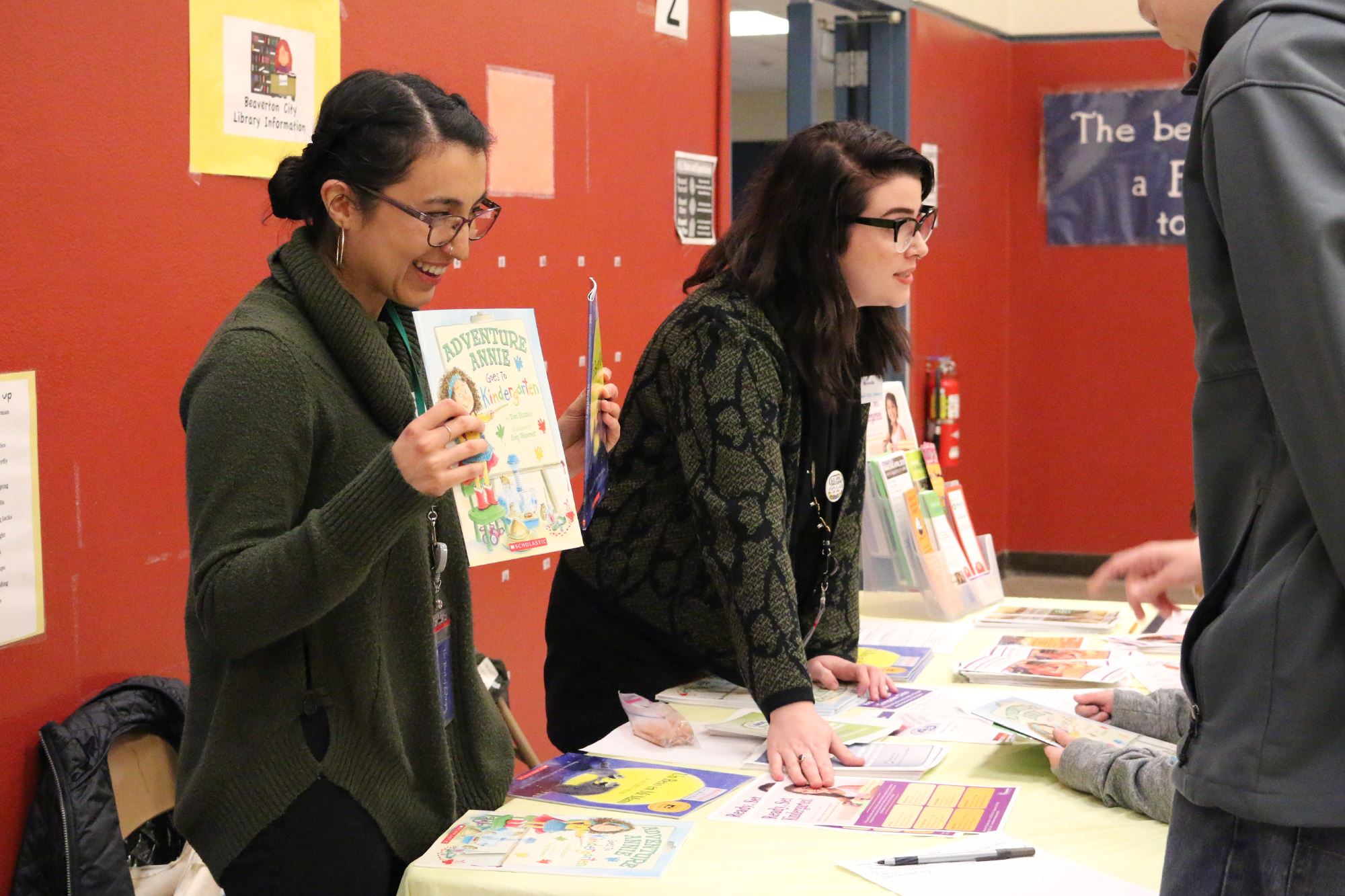 Photo of two people standing at a table with many printed pieces of information.
