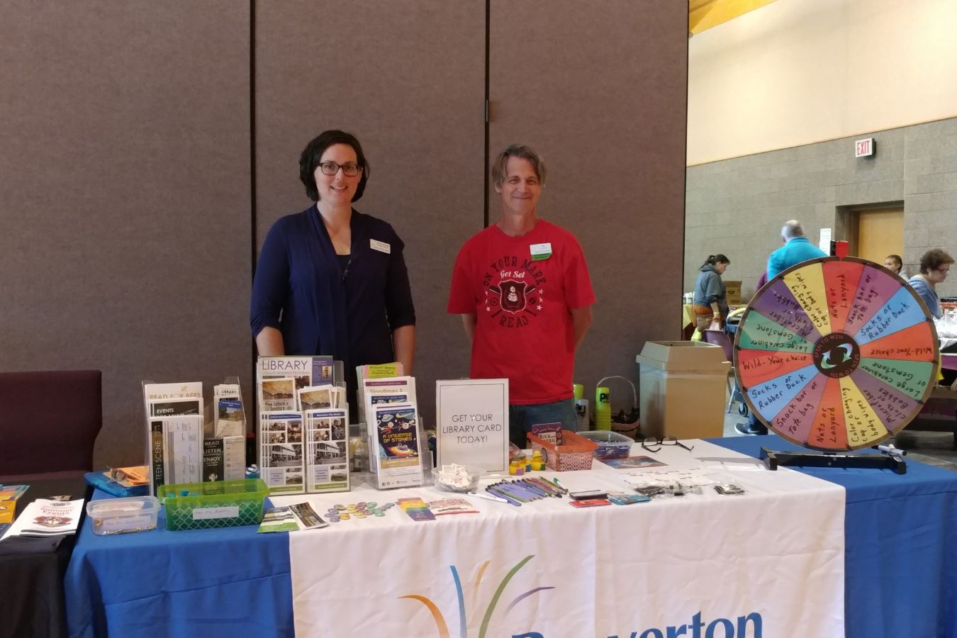 Photo of a woman and a man standing at a table with many printed pieces of information.