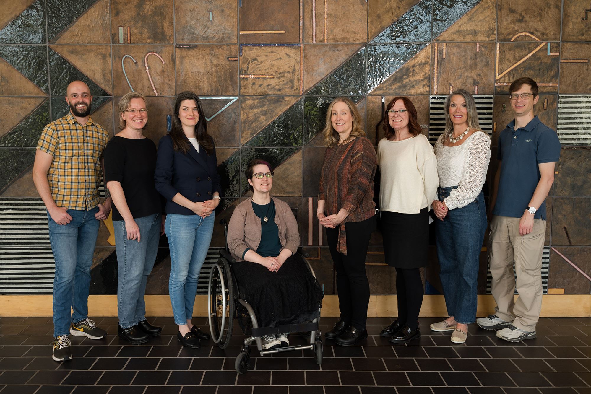 Eight people, members of the Beaverton City Library Advisory Board, in front of a stone mural.